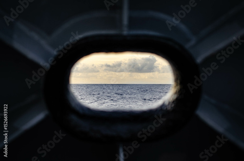 A beautiful view of the horizon in ocean through the ship fairlead - on opening in the ship hull for the mooring ropes. It allows to moor the vessel in port. photo