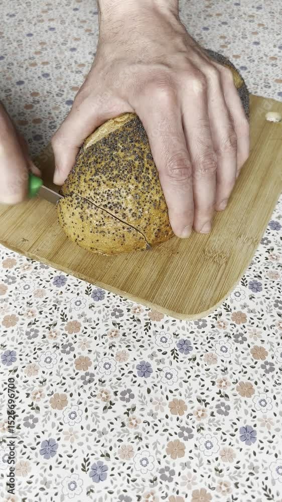 Vertical close-up of fresh crusty bread being sliced with a knife. Crunchy sound, golden crust, and soft texture inside. Cozy, appetizing scene.