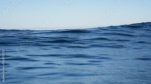 Blue Ocean Surface In Daylight Showing Gentle Waves under Clear Sky with Horizon in Distance