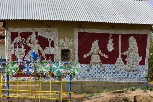 A wall adorned with intricate Alpana art, depicting figures and patterns.