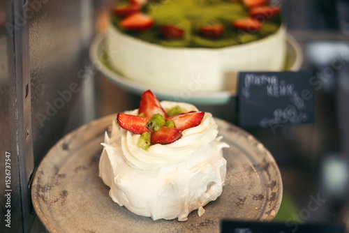 Desserts on display, Pavlova embellished with fresh fruit, strawberries.