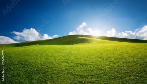 green field and blue sky lawn with short grass on a small hill sun shining from behind