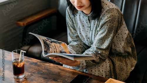 カフェのソファに座って雑誌を読む若い女性