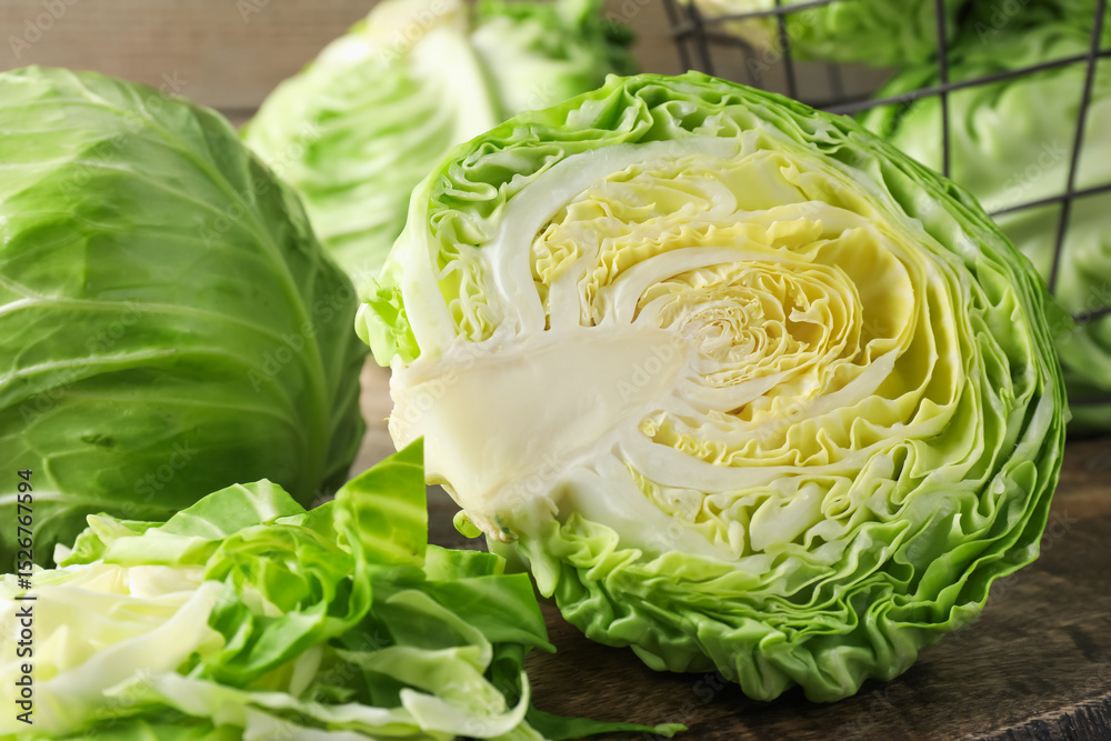 Fototapeta premium Fresh cut and whole cabbages on wooden table, closeup