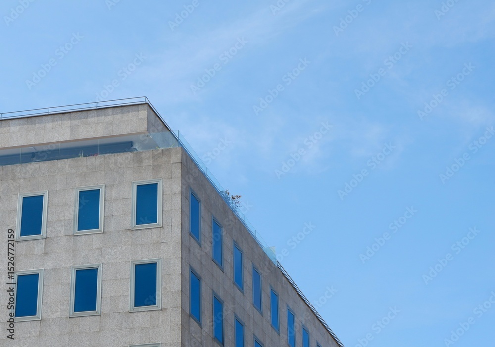 Fototapeta premium A contemporary building with large windows stands against a bright blue sky