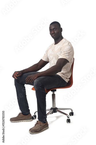 side view of a man sitting on a chair looking at camera on white background