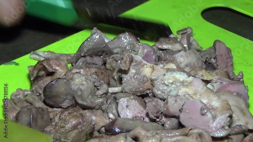 Person slicing boiled chicken offal on a cutting board