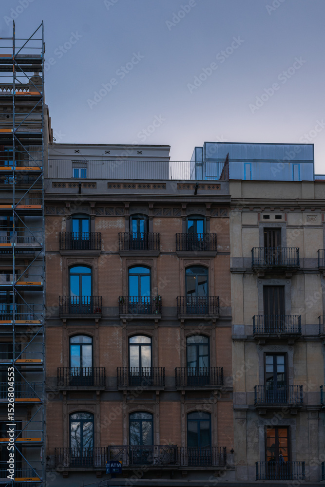 Fototapeta premium Historic Apartment Buildings with Modern Rooftop Structure at Dusk in Barcelona