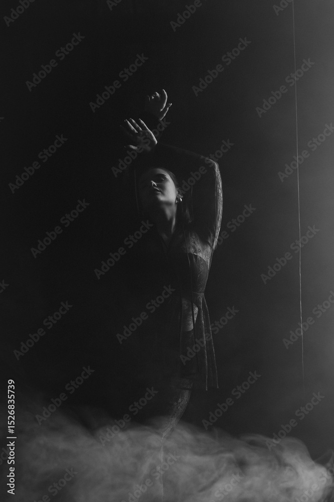 Fototapeta premium A mysterious woman stands in silhouette against a bright window, surrounded by dramatic smoke and shadows