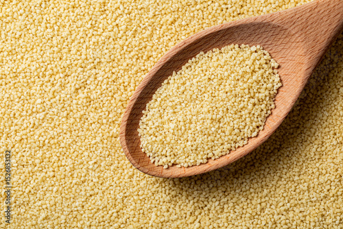 Couscous grains scooped up by a wooden spoon