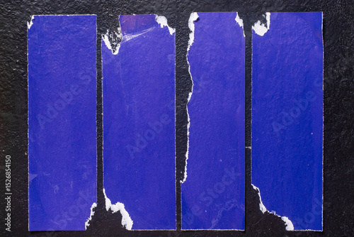 Blue torn poster on black background close-up.