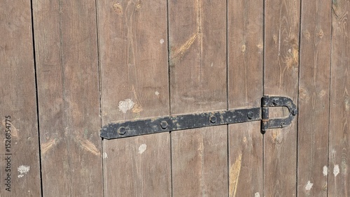 Close-up of wooden door with black metal latch and rustic texture