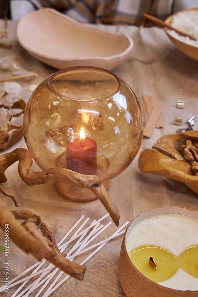 Obraz premium A creative workspace with tools, wax, dried flowers, and a ceramic bowl during the process of making a handmade candle. A cozy and aesthetic DIY moment