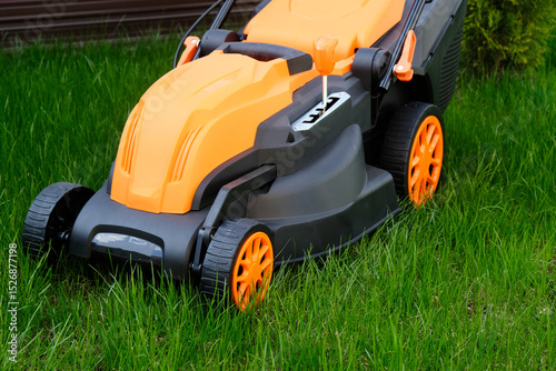 New electric lawn mower against the background of  country house lawn.