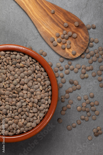 Earthenware bowl full of lentils on a white background in an zenithal photograph
