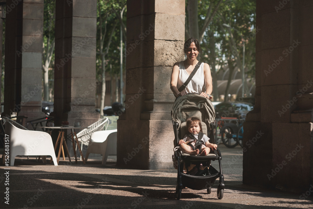 Obraz premium A woman is pushing a stroller with a baby in it