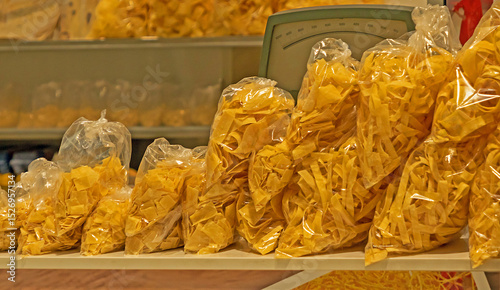 Pile of homemade raw dry pasta in plastic bags sold from market stall