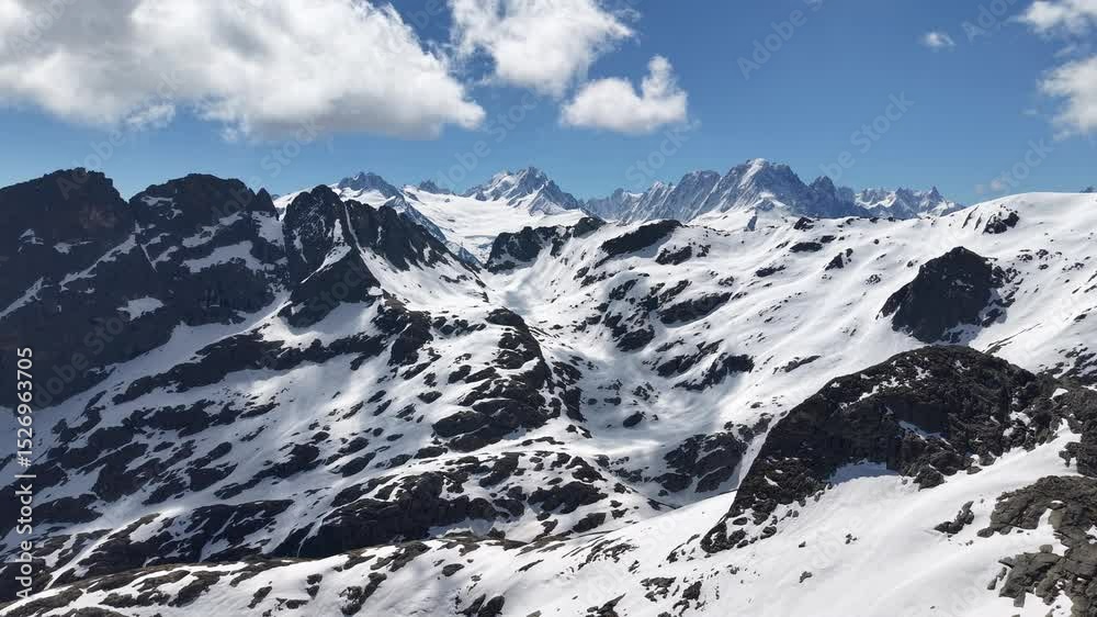 Vue aérienne spectaculaire d’un barrage en arc au cœur des Alpes, entouré de neige et de montagnes rocheuses. Vidéo drone 4k 60fps