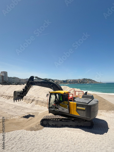 Excavator moving sand on the beach on a sunny day