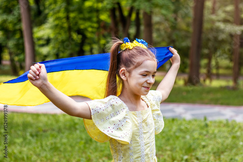 Girl in a yellow dress holding a national flag outdoors in the park