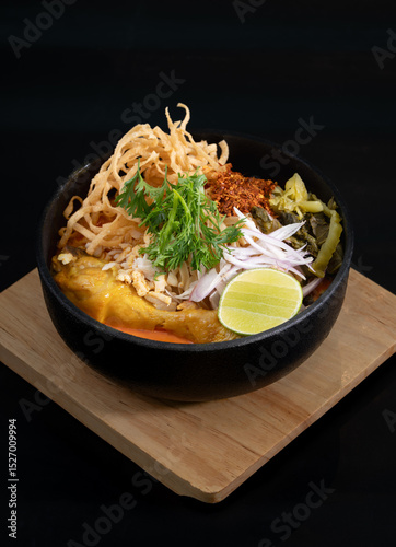 A bowl of Northern Thai curry noodles with chicken thigh or Kao Soi in Thai. Khao Soi is a creamy and slightly spicy yellow curry dish unique to Northern Thailand.