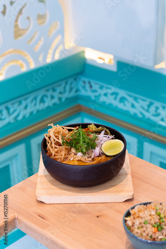 A bowl of Northern Thai curry noodles with chicken thigh and assorted vegetable or Kao Soi in Thai. Khao Soi is a creamy and slightly spicy yellow curry dish unique to Northern Thailand.