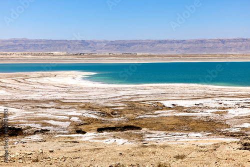 Wallpaper Mural Visitors admire the stunning contrast between the vivid blue water and the surrounding salt formations at the Dead Sea in Jordan. This serene location offers a glimpse of nature's beauty Torontodigital.ca