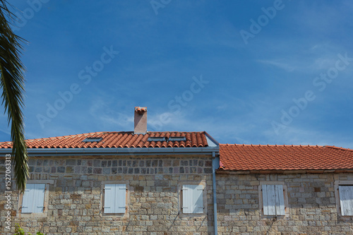 Fototapeta Naklejka Na Ścianę i Meble -  Old stone house with small windows, tiled roof and blue sky on the Adriatic coast in Montenegro Petrovac