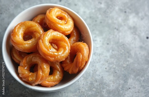 Delicious golden syrup-drenched South African koeksisters donuts in white bowl. Traditional fried, twisted dough pastry. Sweet dessert treat, popular confectionery from South Africa.