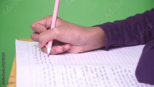 Close up girl's hand is writing in a book, making notes on a diary, green color background