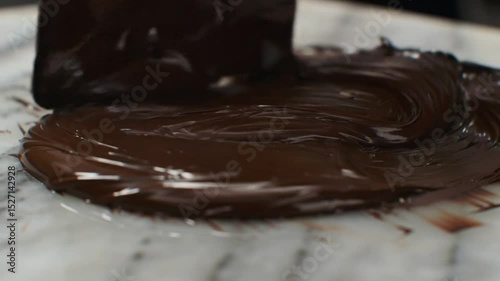 Chocolate tempering on marble slab, glossy ribbon flow