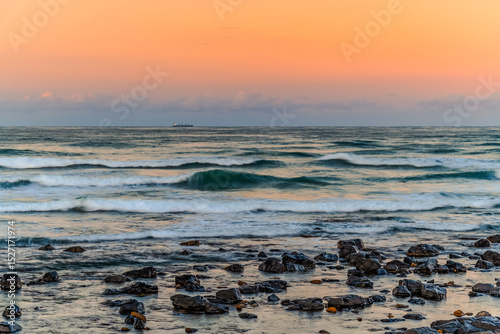 Sunset at the Seaside with black rocks photo