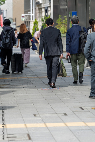 фотографія Business professionals and pedestrians walk along a city sidewalk, reflecting the bustling nature of urban life and showcasing a typical weekday with individuals commuting or heading to work