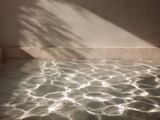 Sunlight creating ripples on water surface with shadows on beige wall, natural light