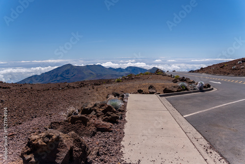 Haleakala National Park landscape with a road, rocks, and mountains under a blue sky.