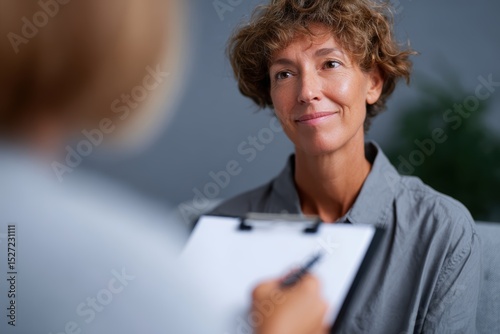 Female therapist holding clipboard and nodding in counseling session