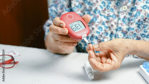 Elderly person checking blood sugar level with glucose meter, hand holding device and test strip, diabetes management at home, health care concept