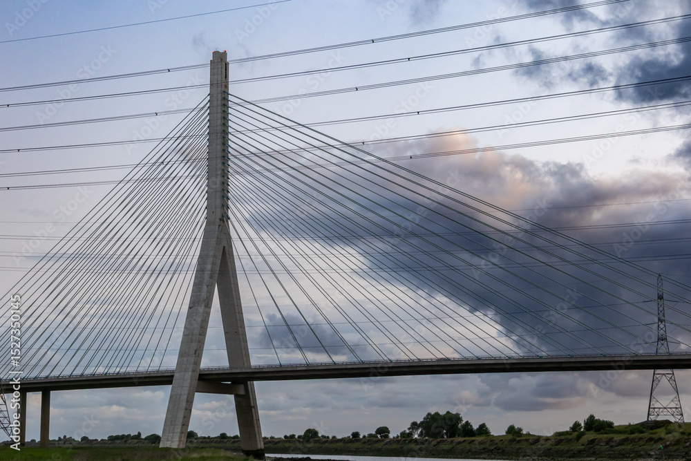 Flintshire Bridge's main pylon and cables are silhouetted against a cloudy sunrise Flintshire Bridge's main pylon and cables are silhouetted against a cloudy sunrise