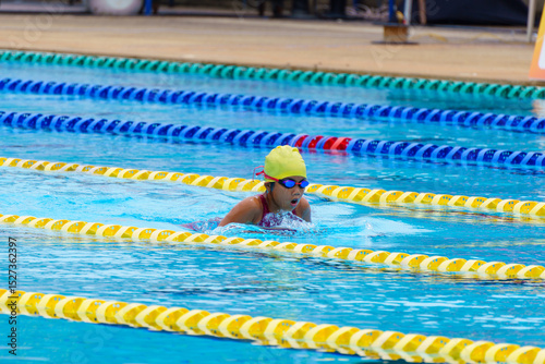 Swimmer child swims breaststroke swimming style in a race swimming pool. Water sports and competition, learning to swim classes for children.