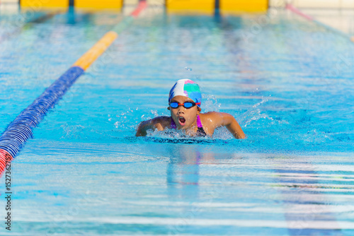 Swimmer child swims butterfly swimming style in a race swimming pool. Water sports and competition, learning to swim classes for children.