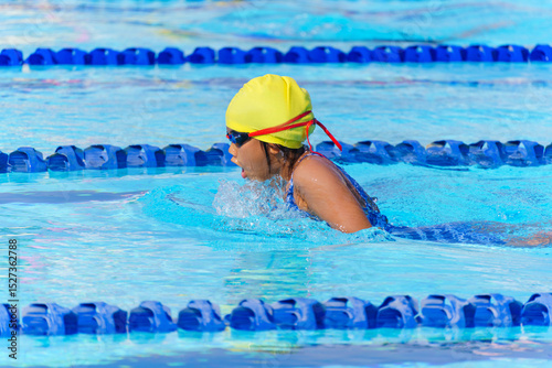 Swimmer child swims breaststroke swimming style in a race swimming pool. Water sports and competition, learning to swim classes for children.