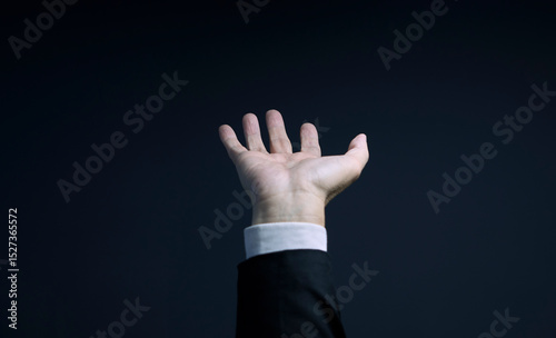 Businessman reaching out with open hand on dark background