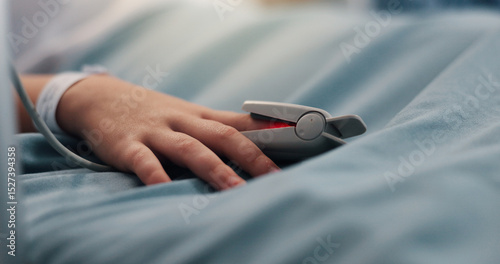 Hand, child and pulse oximeter on hospital bed to measure blood levels, monitor and recovery. Closeup, young patient and resting with medical machine, track oxygen and critical care from procedure photo