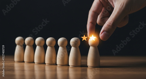 Hand selecting a wooden figure with glowing stars from a row of similar wooden figures on a table business.selling ,purchasing,agreement 