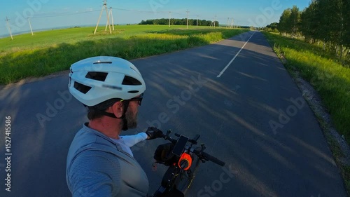 man riding bike at sunset outside city and filming video for blog, solo bike trip