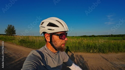 man riding bike at sunset outside city and filming video for blog, solo bike trip