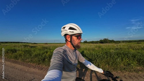man riding bike at sunset outside city and filming video for blog, solo bike trip