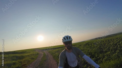 man riding bike at sunset outside city and filming video for blog, solo bike trip