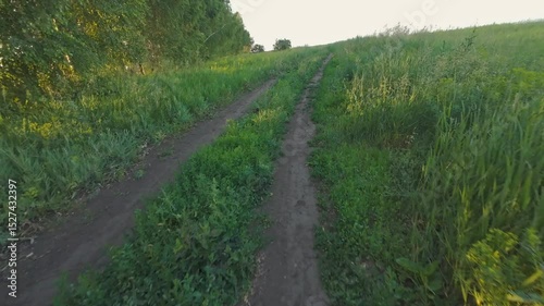 Riding on a dirt country road in summer in a field at sunset
