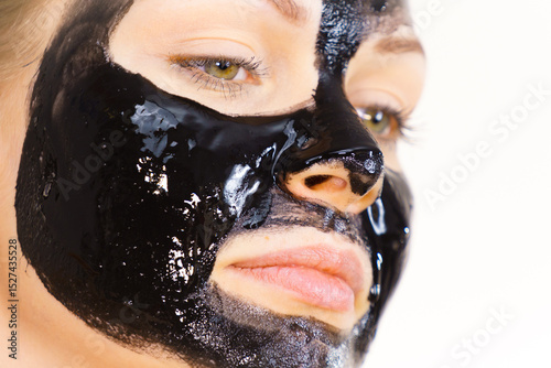 Woman applying black cleanser mask to face